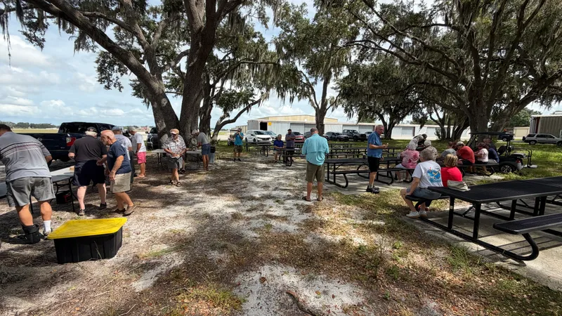 Members gathered at picnic tables under the oaks beside the hangars at Winter Haven Regional Airport