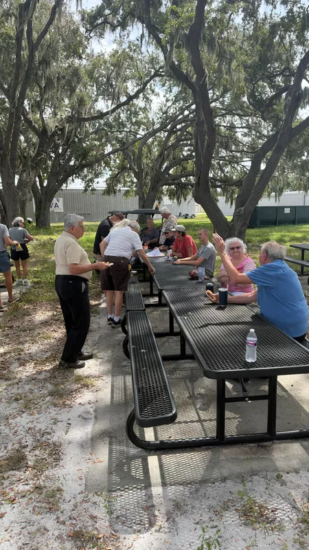 Members seated at the picnic tables, one waving to the camera